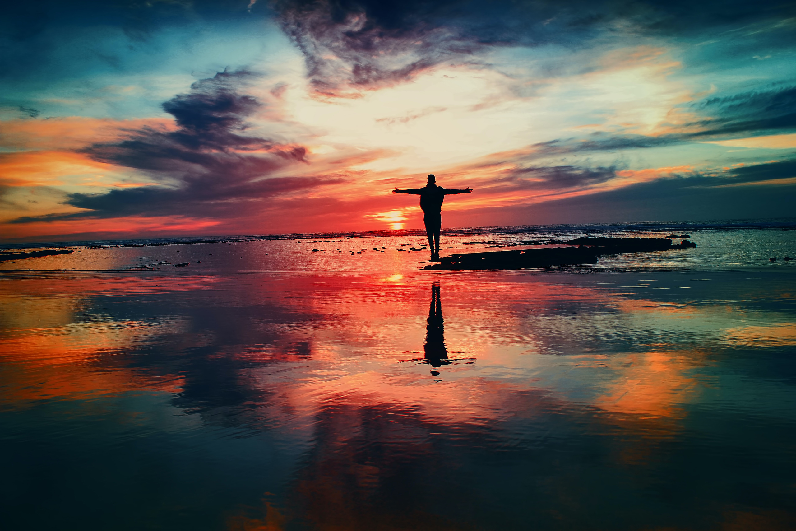 Man with arms stretched out on beach sunset-1